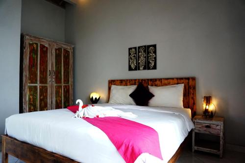 a bedroom with a large white bed with a red blanket at Louto Dmell Villa & Guesthouse in Sanur