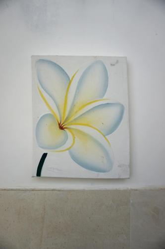 a painting of a blue and white flower on a wall at Louto Dmell Villa & Guesthouse in Sanur