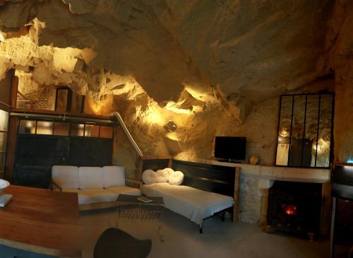 ein Wohnzimmer mit einem Sofa und einem Kamin in der Unterkunft La Grotte du Moulin in Noyers-sur-Cher