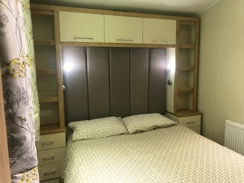 a bedroom with a bed with a wooden headboard at Poppy at Oakdene Forest Park in Ringwood