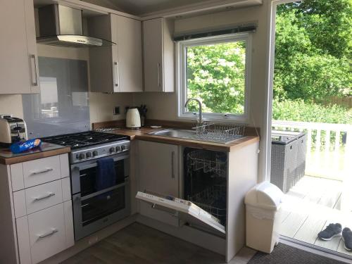 a kitchen with a sink and a stove and a window at Poppy at Oakdene Forest Park in Ringwood