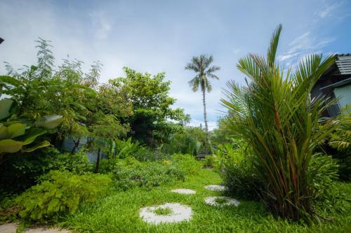 a garden with plants and a palm tree in the background at Trat 101 Hotel - SHA Certified in Trat