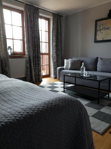 a bedroom with a bed and a couch and windows at Majątek Morgi in Suchowola
