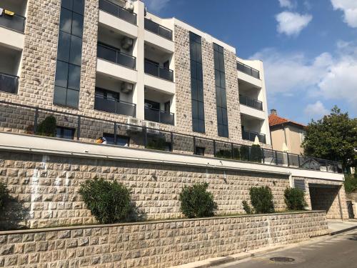 a brick retaining wall in front of a building at Apartments Bane in Herceg-Novi