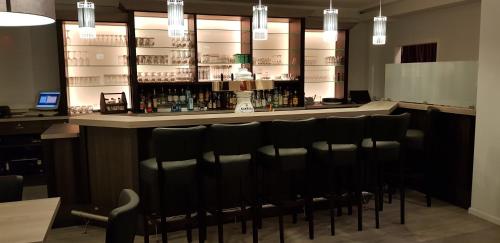 a bar with a row of black chairs in a restaurant at Hotel Restaurant Teichaue in Adendorf