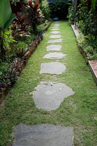 a walkway in a garden with grass and rocks at Louto Dmell Villa & Guesthouse in Sanur