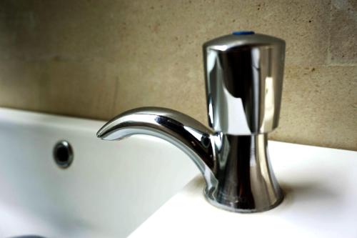 a silver faucet on a sink in a bathroom at Louto Dmell Villa & Guesthouse in Sanur