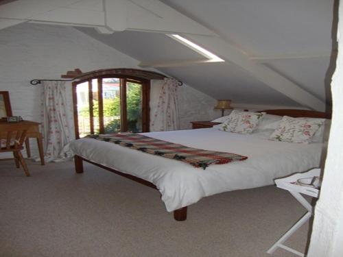 a bedroom with a large white bed with a window at Church Barn in Harberton