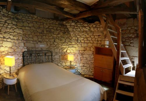 a bedroom with a bed and a stone wall at Le Moulin de la Motte Baudoin in Noyers-sur-Cher