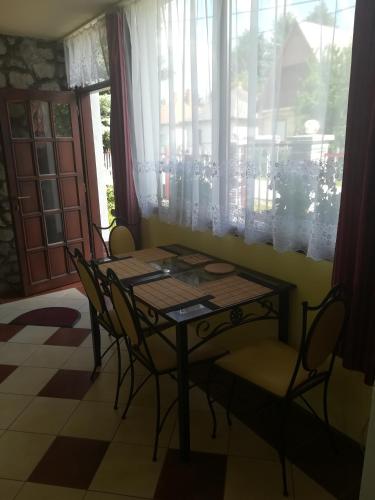 Una mesa y sillas en una habitación con ventana. en Derű Apartman, en Mezőkövesd