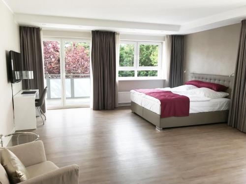 ein Schlafzimmer mit einem Bett, einem TV und einem Sofa in der Unterkunft TH39 Trend Hotel in Bad Vilbel