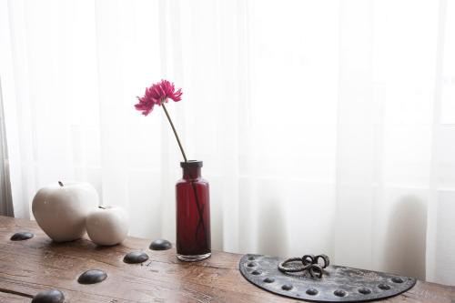 a red vase with a flower in it on a table at Quentin Prague Hotel in Prague
