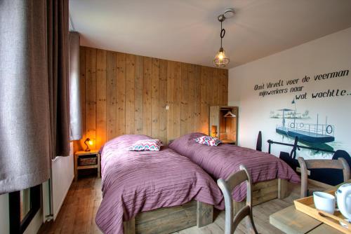 two beds in a room with wooden walls at Bed & Breakfast 't Vèèrke in Dilsen-Stokkem