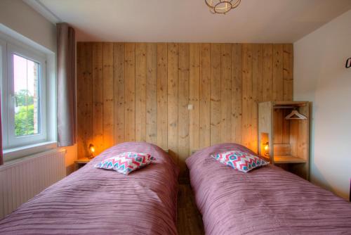 two beds in a bedroom with wooden walls and a window at Bed & Breakfast 't Vèèrke in Dilsen-Stokkem