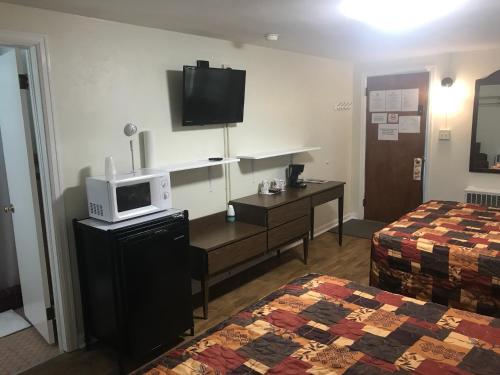 a hotel room with a bed and a microwave on a desk at Evergreen Motel in Oswego
