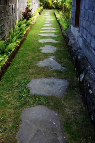 a stepping stone path in a garden with plants at Louto Dmell Villa & Guesthouse in Sanur
