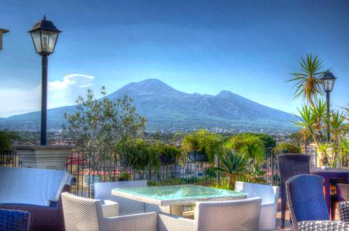 a patio with a table and chairs and a mountain at Hotel Palma in Pompei