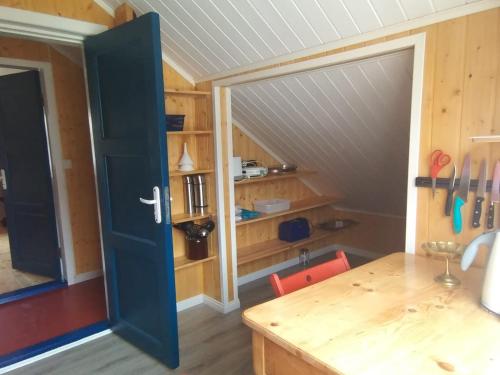 a kitchen with a blue door and a wooden table at Blue House II at the end of the World in Mehamn