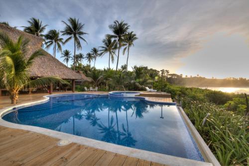 a pool at a resort with palm trees at Mandala Eco Villas in La Libertad