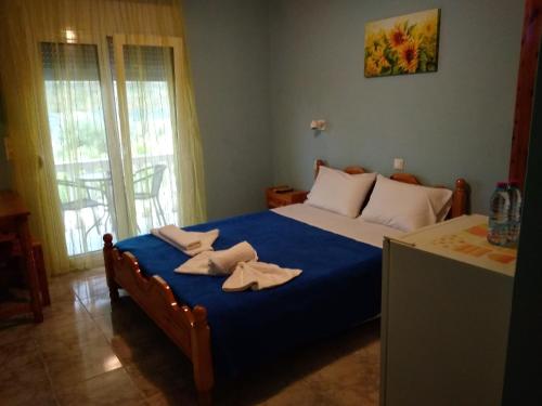 a bedroom with a blue bed with towels on it at Stamatia Rooms in Parga
