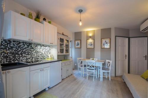 a kitchen with white cabinets and a table at Apartments Villa Anka in Komiža