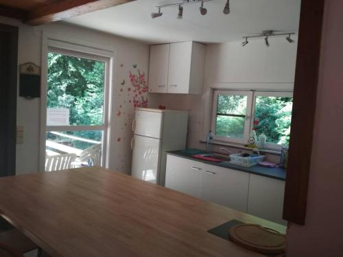 a kitchen with a table and a refrigerator at Chalet - Au retour vers Soi in Les Nobertins