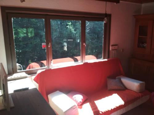 ein rotes Sofa in einem Zimmer mit einem großen Fenster in der Unterkunft Chalet - Au retour vers Soi in Les Nobertins