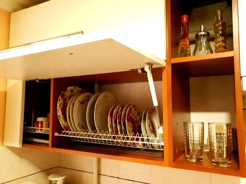 ドニプロにあるApartment Ushakova 16の皿とグラスが入ったキッチンキャビネット