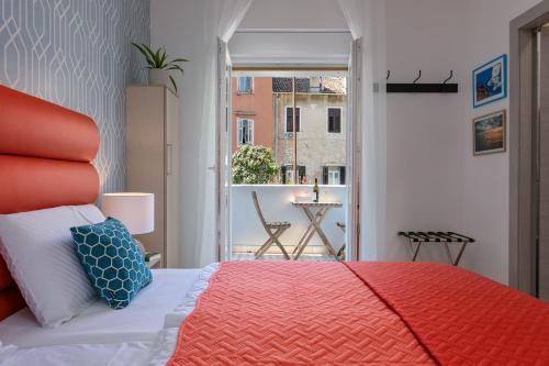 a bedroom with a red bed and a balcony at La Preziosa Rooms in Pula