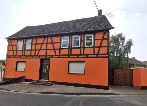 una casa naranja con techo negro en Ferienwohnung Götze en Irxleben