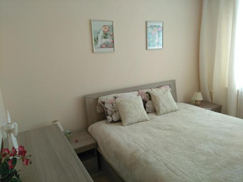 a bedroom with a bed with two pillows and a table at Dzintari in Liepāja