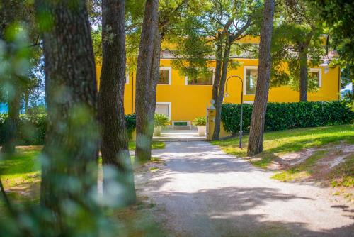 a yellow house with a pathway in front of it at Tra gli Alberi e il Mare in Sirolo