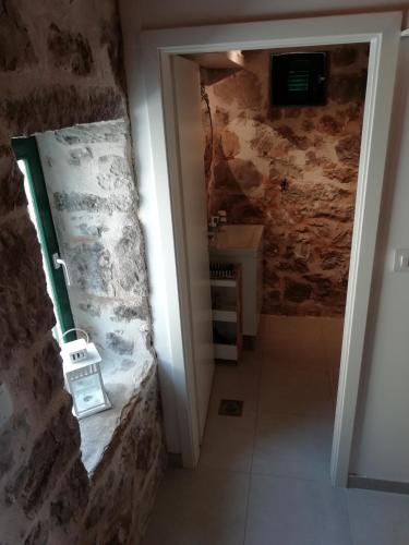 a small bathroom with a stone wall and a sink at Krka Waterfalls Stonehouse Roko in Lozovac