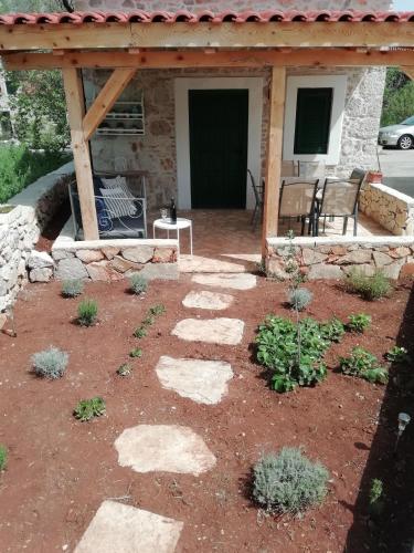 a patio with rocks and a wooden pergola at Krka Waterfalls Stonehouse Roko in Lozovac