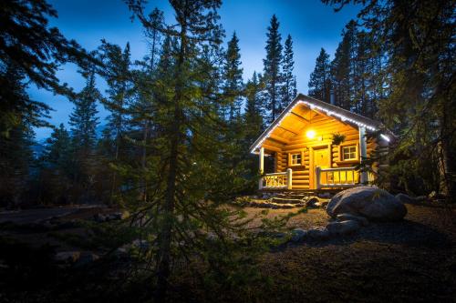 a log cabin in the woods at night at Storm Mountain Lodge & Cabins in Banff