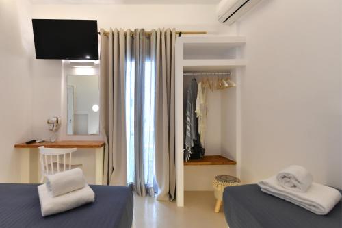 a bedroom with two beds and a tv and a closet at Ammos Luxury Rooms & Home in Naousa