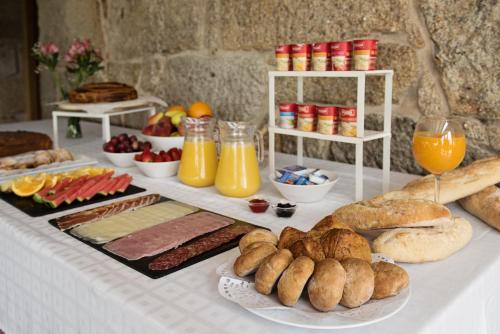 a table topped with lots of different types of bread and orange juice at Casa Rural Abadia Eiras in Rosal