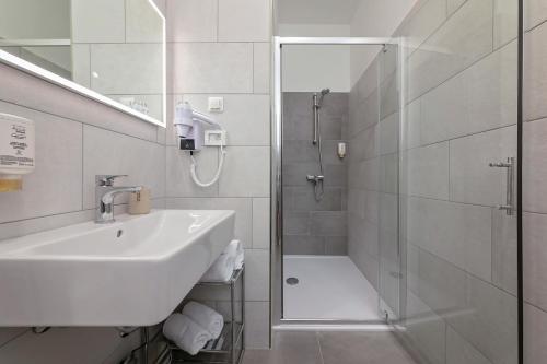 a white bathroom with a sink and a shower at La Preziosa Rooms in Pula