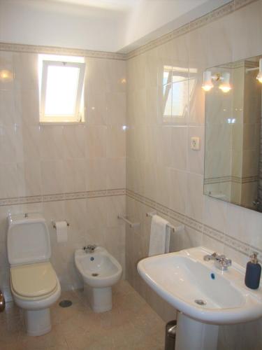 a white bathroom with a toilet and a sink at Belinha Guest House in Luz