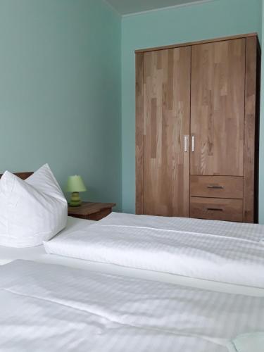 a bedroom with a large white bed with a wooden cabinet at Gasthof Lindenkrug in Broderstorf
