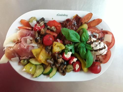 a white plate of food with a salad on it at Gasthof Lindenkrug in Broderstorf
