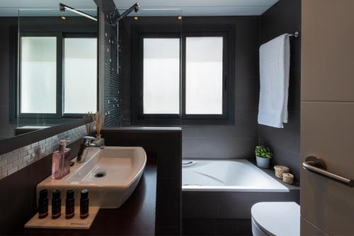 uma casa de banho com um lavatório, uma banheira e um WC. em Sitges Centre. Simply Charming em Sitges