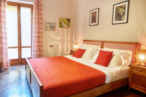 a bedroom with a large bed with red pillows at Residence Domaso - Esperienza in Centro Storico "Casa del Dottore" in Domaso