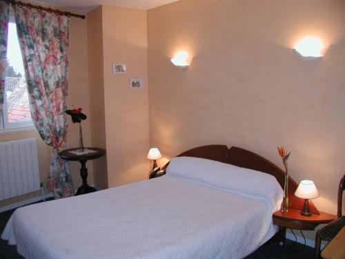 a bedroom with a white bed and two lamps at Hôtel Auberge de La Nauze in Sagelat