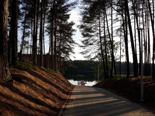 a path next to a lake with trees and a bench at Mazurskie Klimaty Tatarak in Olsztyn