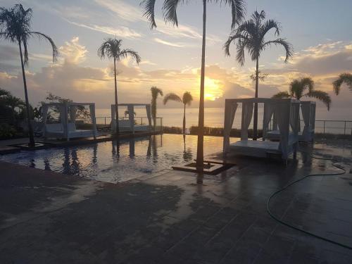a pool with chairs and palm trees and the ocean at Apartamento El Palmar Residences in San Carlos