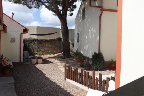 a fence next to a building with a tree at Casa o Futuro in Alcobaça
