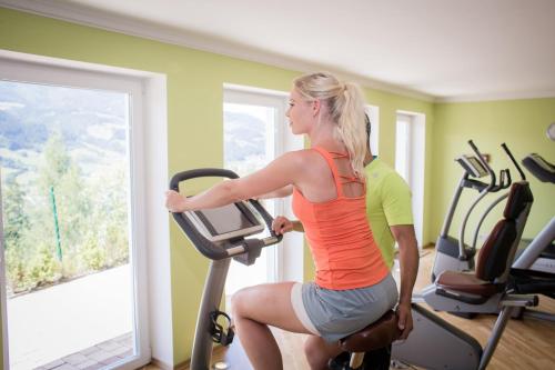 a man and a woman on a treadmill in a gym at Hotel AlpenSchlössl in Sankt Johann im Pongau