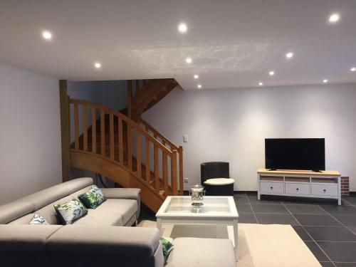 a living room with a couch and a television at Au domaine des roches in Saint-Pierre-sur-Dives
