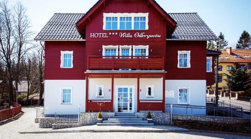 a red and white building with a sign on it at Hotel Willa Odkrywców in Szklarska Poręba